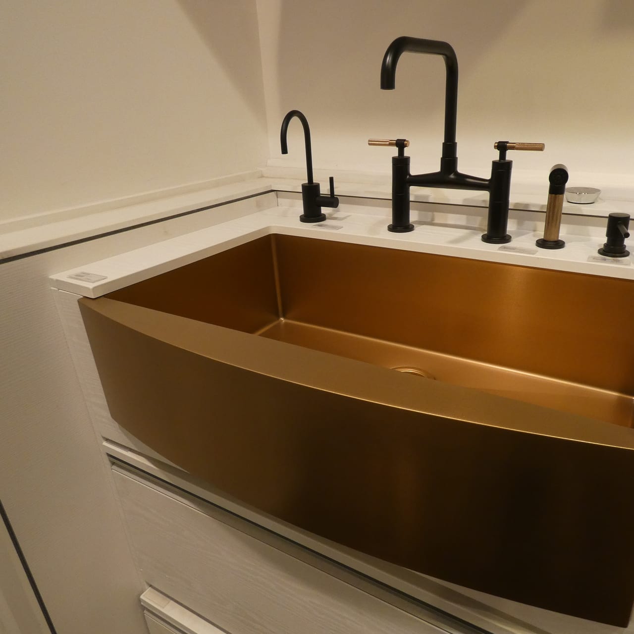 Brass farmhouse sink and black bridge faucet in a fixture display